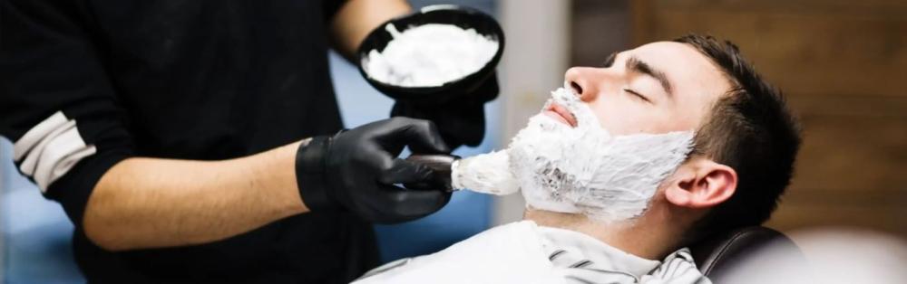 barber shaving customers face on a barber chair