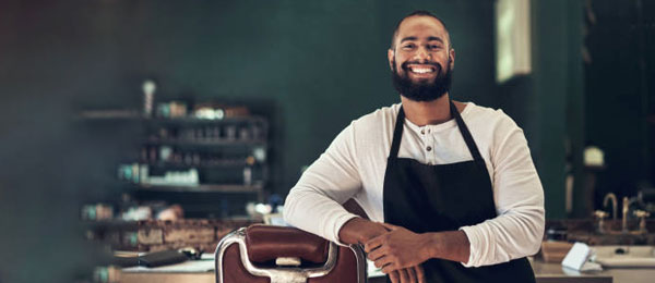 Happy barber in his barbershop